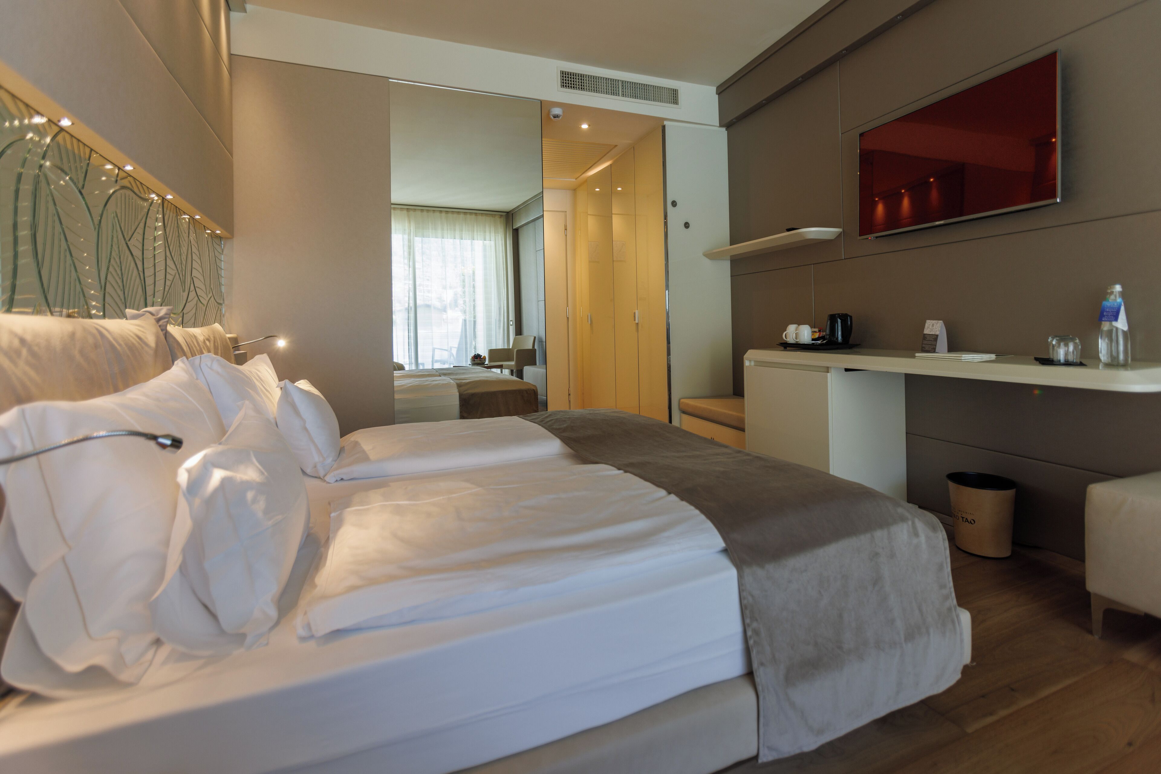 Ein modernes Hotelzimmer mit einem großen Bett, einem Schreibtisch und einem Spiegel.
