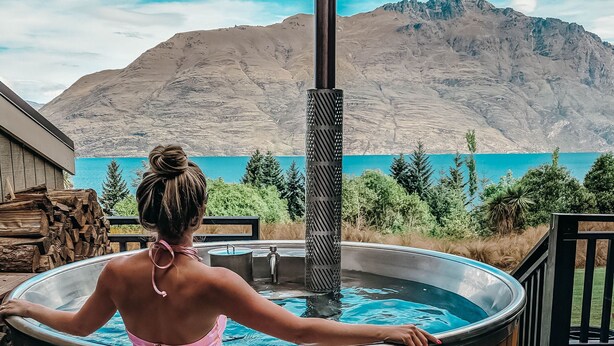 A person relaxing in a wooden hot tub on a deck with a mountain view. - Hidden Lodge Queenstown (Queenstown)