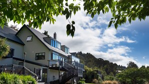 A large, two-story house with a balcony and a staircase leading to the entrance. - Hidden Lodge Queenstown (Queenstown)