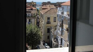 Vista desde una ventana con vista a una calle con edificios y cielo despejado.