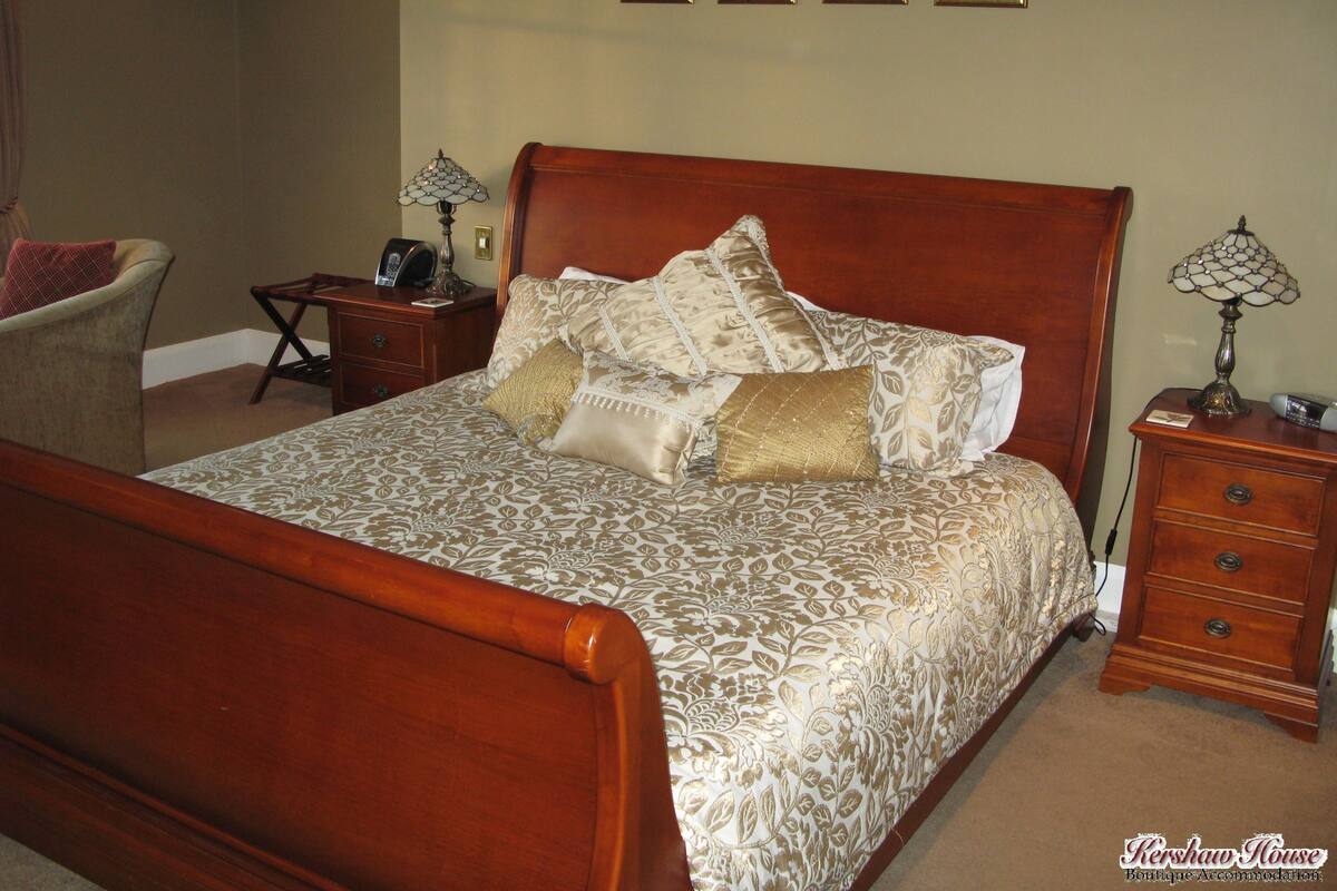A neatly made bed with a patterned bedspread, a wooden headboard, and a bedside table with a lamp.