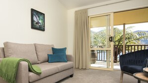 A living room with a beige sofa, blue cushions, a green throw, and a dark blue armchair.
