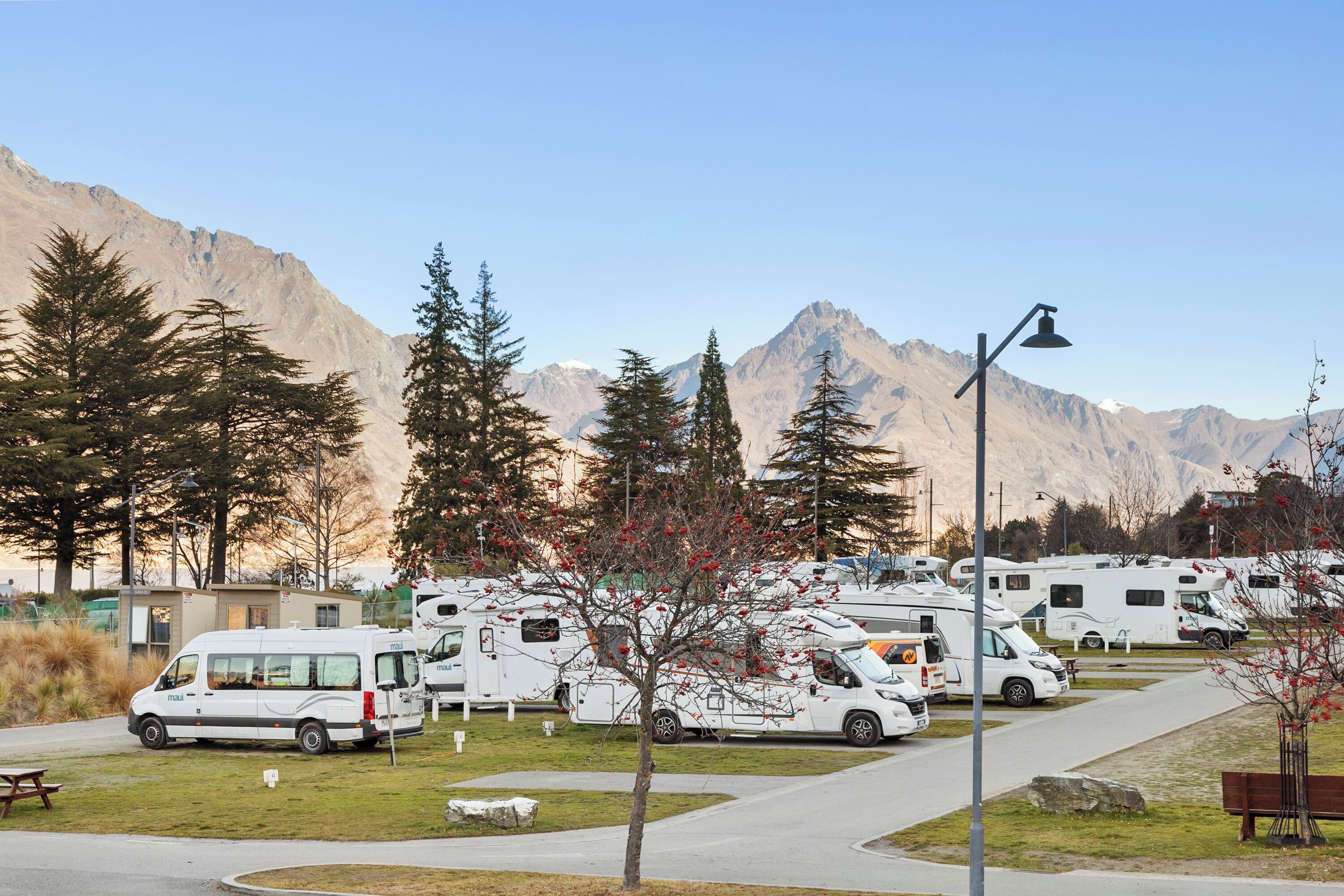 A campground with RVs parked in rows, a picnic table, and a lamp post.