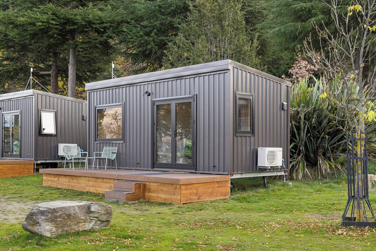Una cabaña moderna y compacta con un área de terraza, asientos integrados y una pequeña cocina exterior.