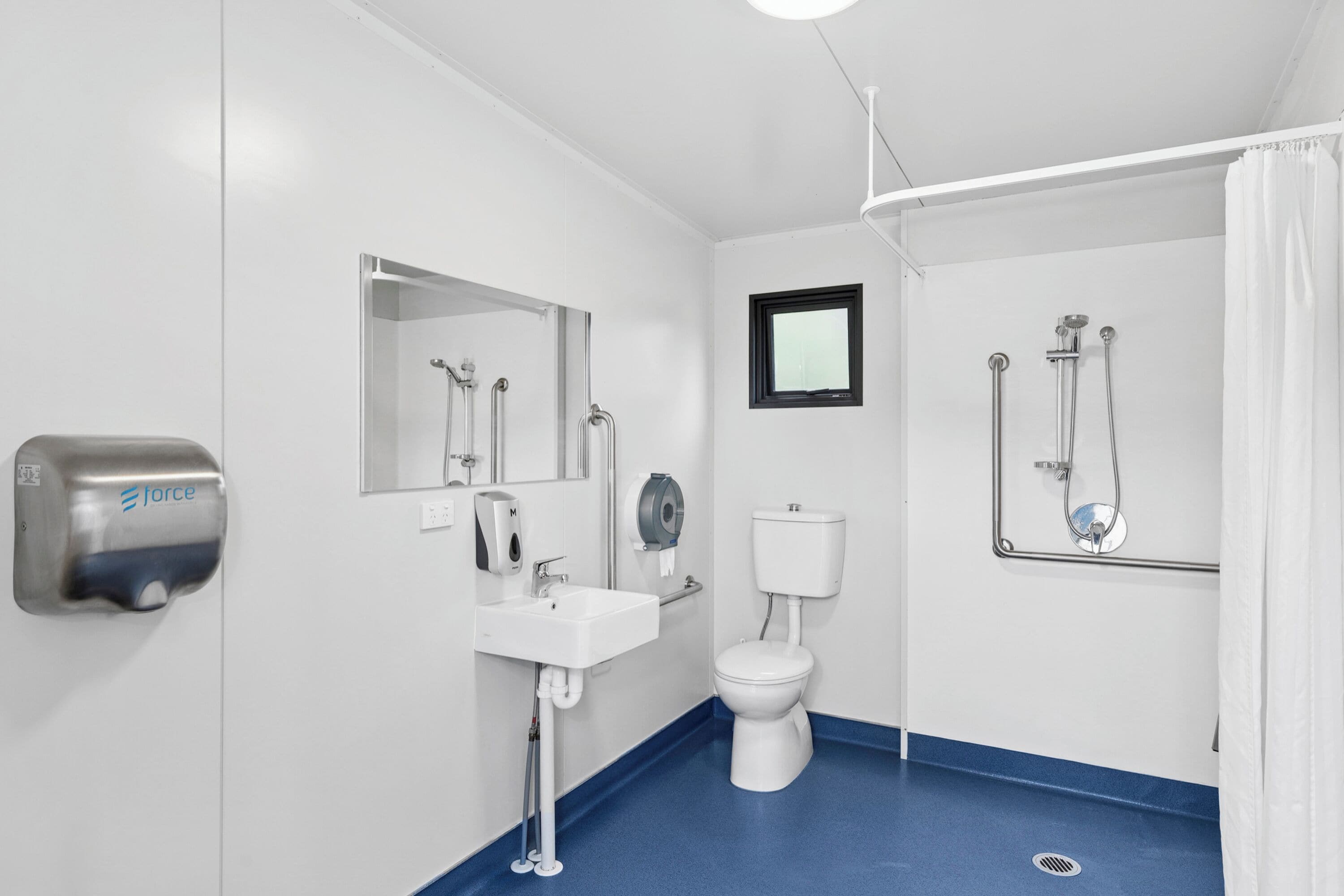 Ein modernes Badezimmer mit Waschbecken, Toilette, Spiegel und Duschbereich.