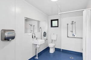 A modern bathroom with a white sink, a toilet, a mirror, and a shower area.