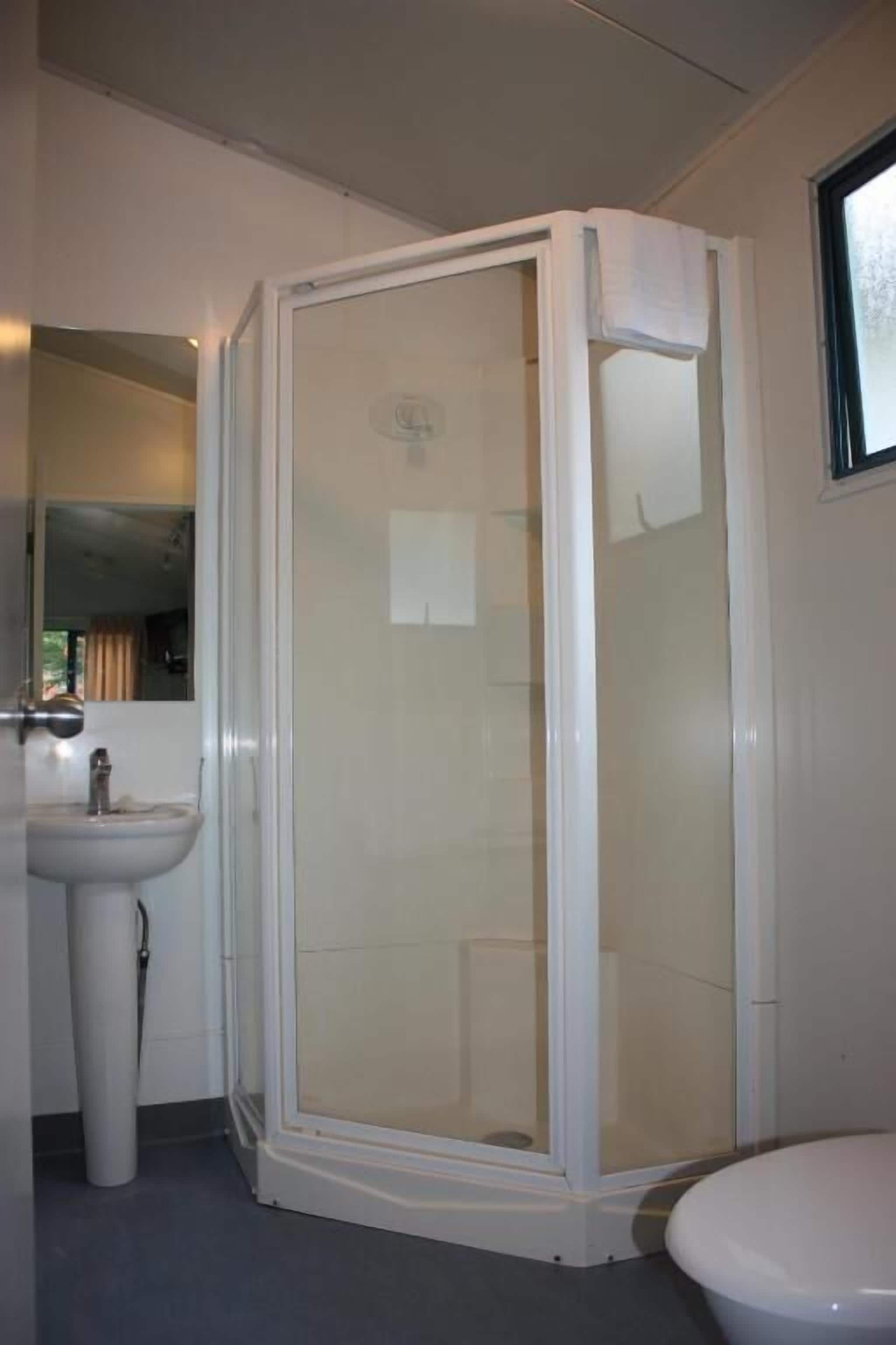 A bathroom with a glass-enclosed shower, a sink, and a toilet.