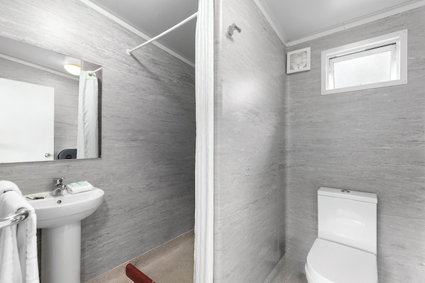 A modern bathroom with a pedestal sink, a toilet, and a shower area. - Hampshire Holiday Parks - Queenstown Lakeview (Queenstown)