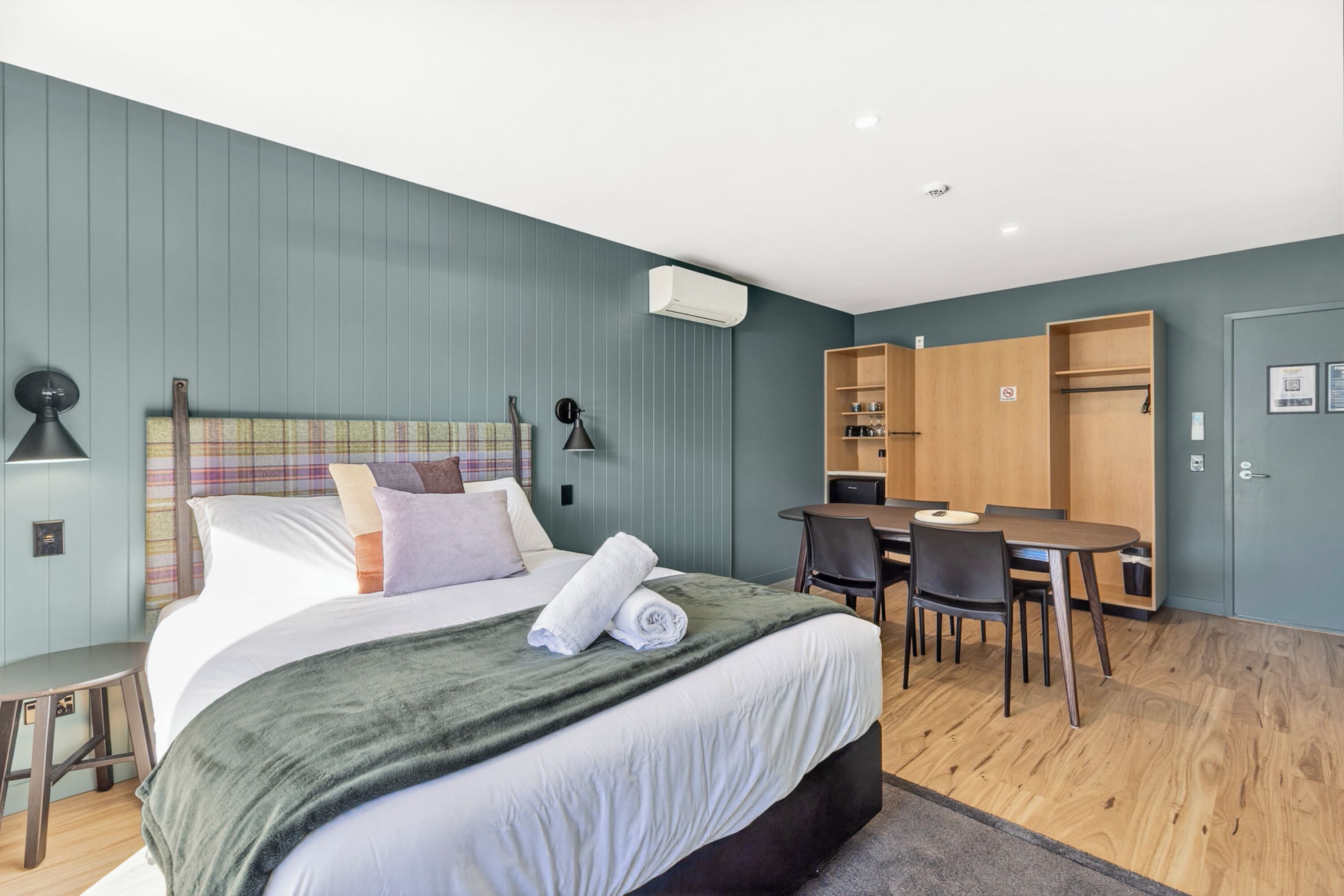 Ett modernt hotellrum med en stor säng, ett skrivbord och en garderob.