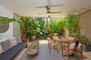 Eine gemütliche Terrasse mit einer Couch, Stühlen, einem Tisch und einem Deckenventilator.