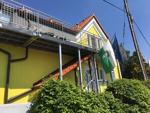 A yellow building with a balcony, a flag, and a staircase.