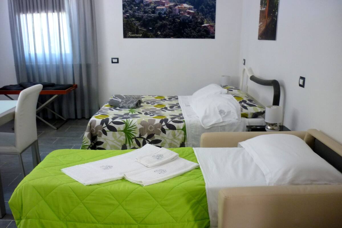 A hotel room with two beds, a desk, and a chair.