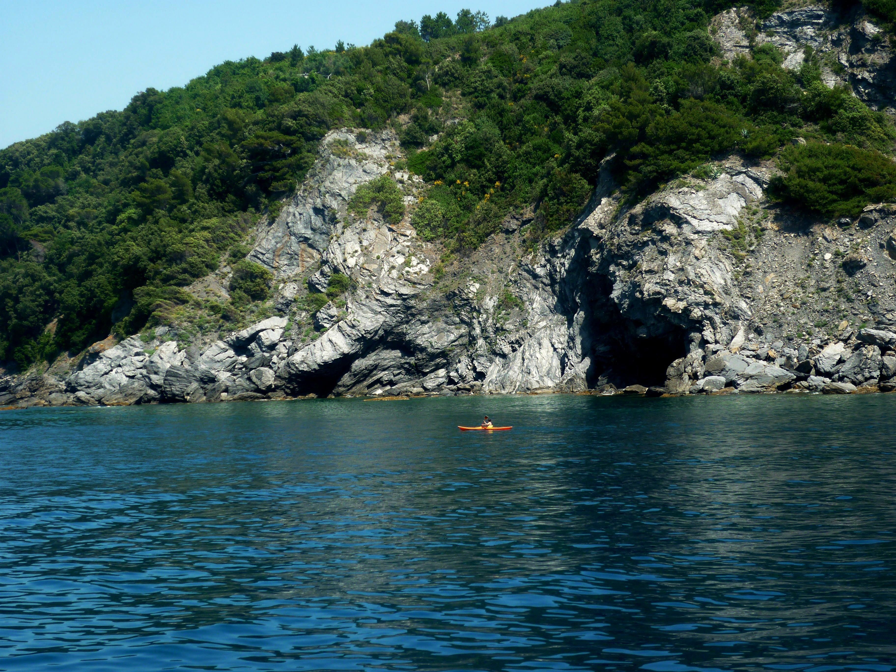 A rocky coastline with a kayaker in the water.