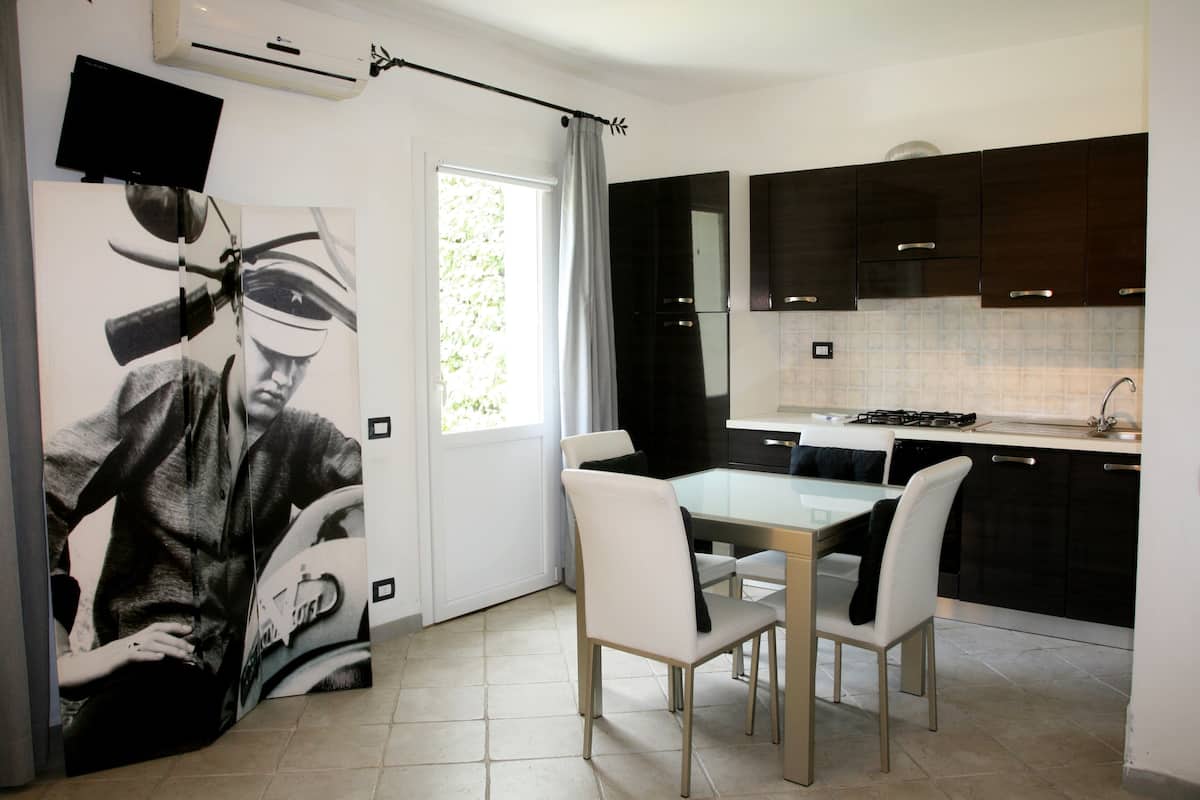A modern kitchen with dark cabinets, a glass dining table, and a large window.