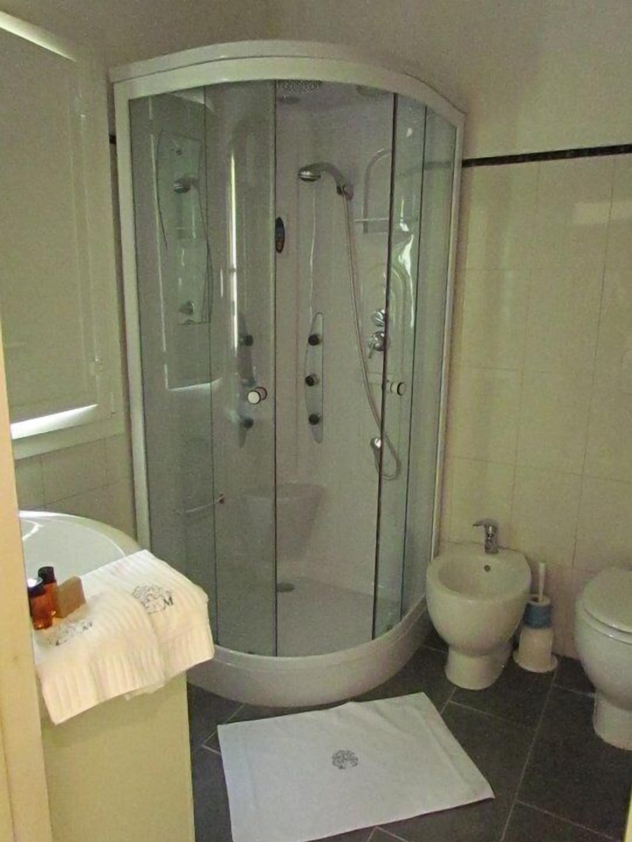 A bathroom with a glass-enclosed shower, a sink, a bidet, and a toilet.