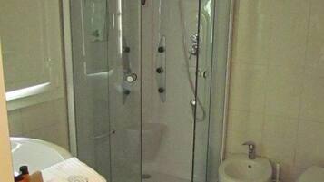 A bathroom with a glass-enclosed shower, a sink, a bidet, and a toilet.