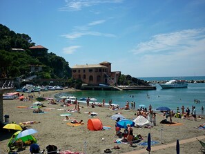 A beach with people sunbathing, umbrellas, and boats in the water. - Resort Costa Morroni (Levanto)