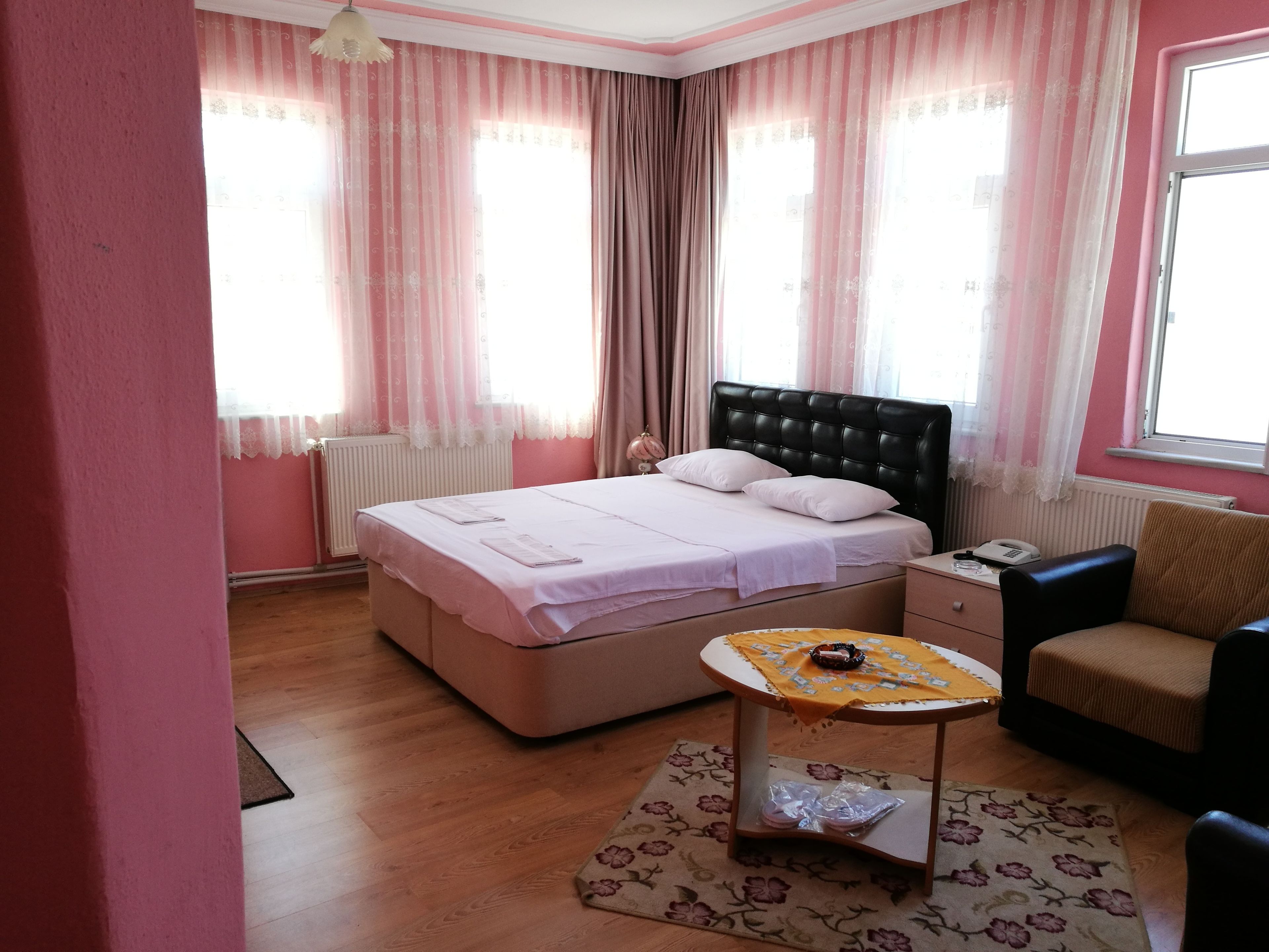 A bedroom with a bed, bedside table, chair, and a small table with a tray.