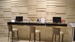A bar area with two laptops, a menu stand, and three bar stools. - Cosmopolitan Hotel (Civitanova Marche)