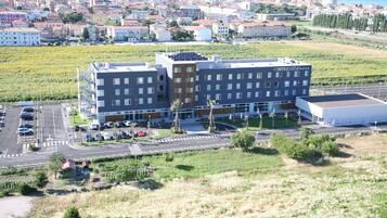A modern hotel with a flat roof, multiple floors, and a parking lot in front.