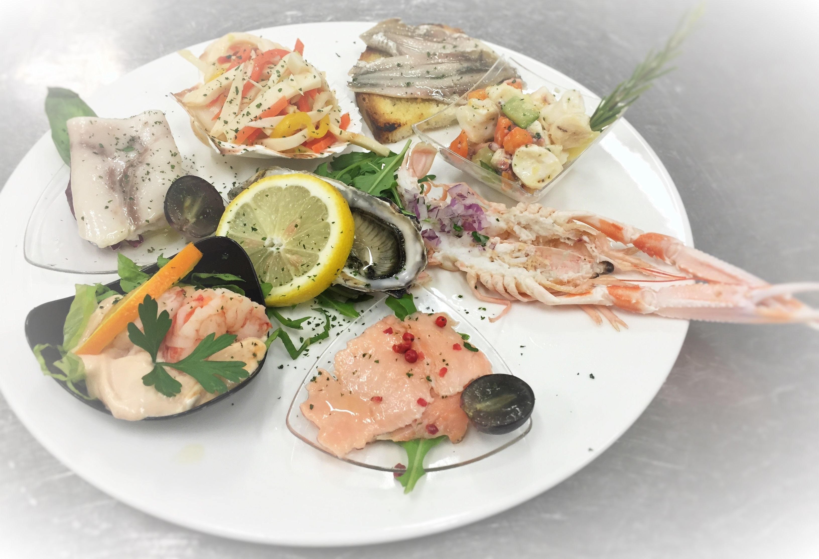 Un plateau de fruits de mer comprenant différents types de poissons, des crevettes et une tranche de citron.