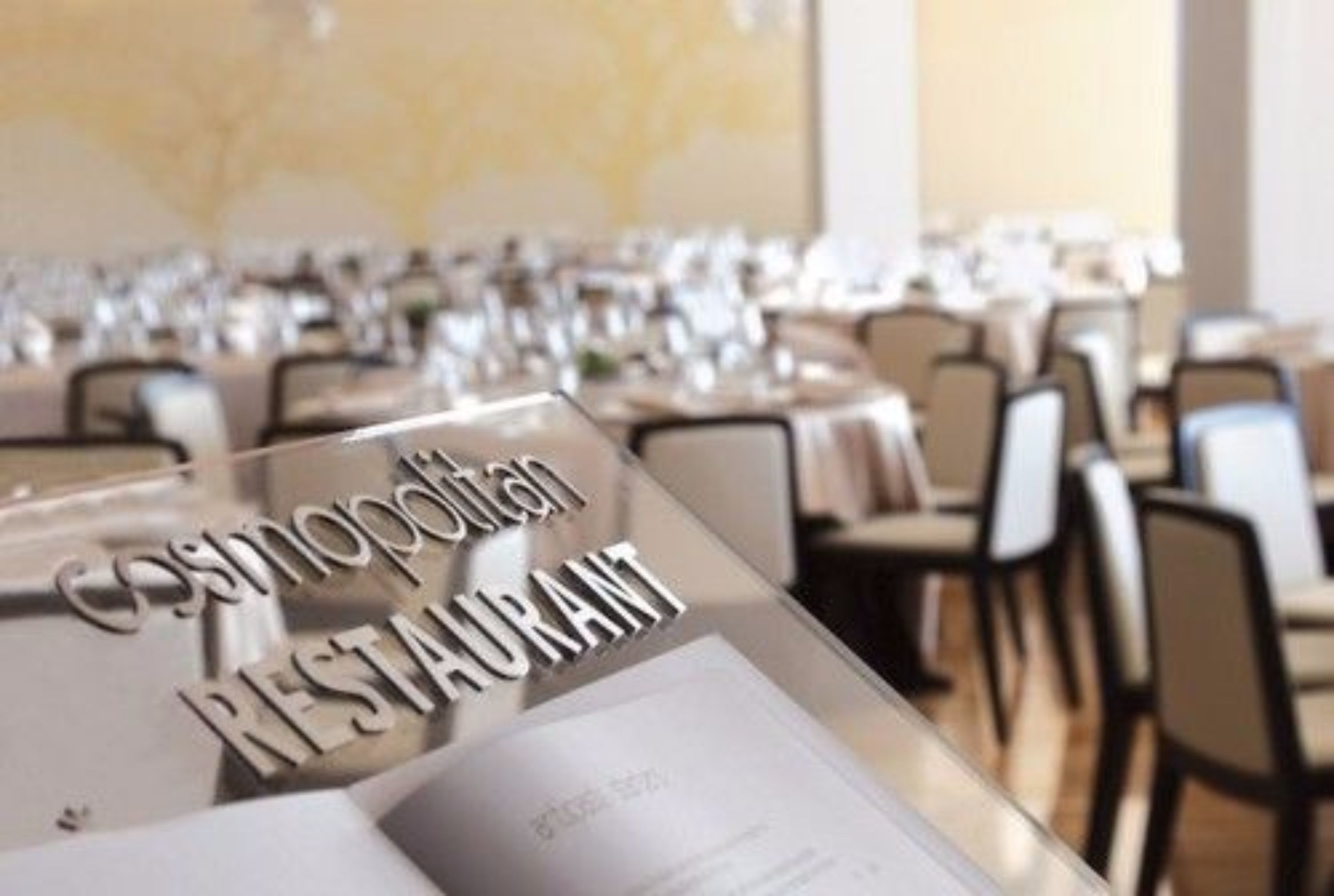 A restaurant interior with tables set for dining, a menu stand, and a wall with a map.