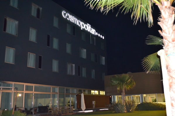 A hotel with a large illuminated sign reading "Cosmopolitan." It features multiple windows and a well-lit exterior.