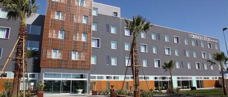 A modern hotel with a flat facade, multiple windows, and a sign reading "Cosmopolitan."