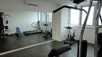 Una palestra con attrezzature per esercizi, tapis roulant e uno specchio.