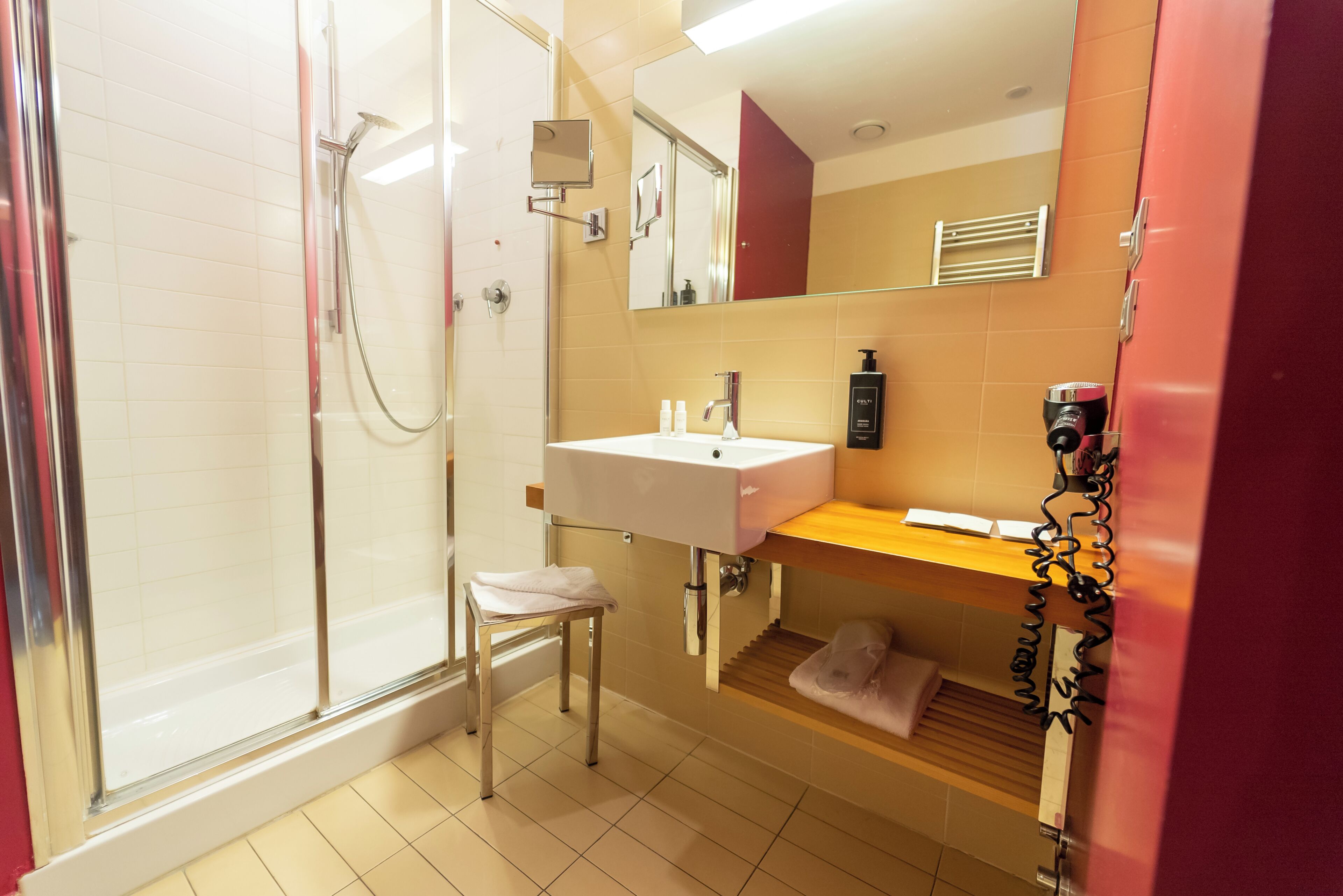 A bathroom with a glass shower enclosure, a white sink, and a mirror above it.