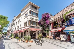 A hotel with a sign reading "HOTEL TAYMANAT" and a cafe named "TAYA CAFE & RESTAURANT" with outdoor seating.