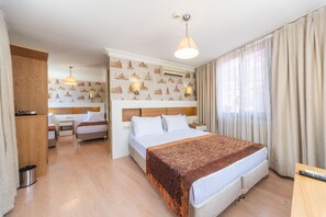 Una habitación de hotel con una cama, mesitas de noche, un escritorio y una ventana con cortinas.