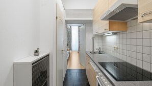 A narrow kitchen with a stove, sink, and cabinets. - AJO Vienna Messe - Contactless Check-in (Vienna)