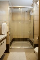 A modern bathroom with a glass-enclosed shower, a white sink, and a toilet.