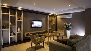 A modern living room with a TV, wooden shelves, a sofa, and a coffee table. - Supreme Marmaris Hotel (Marmaris)