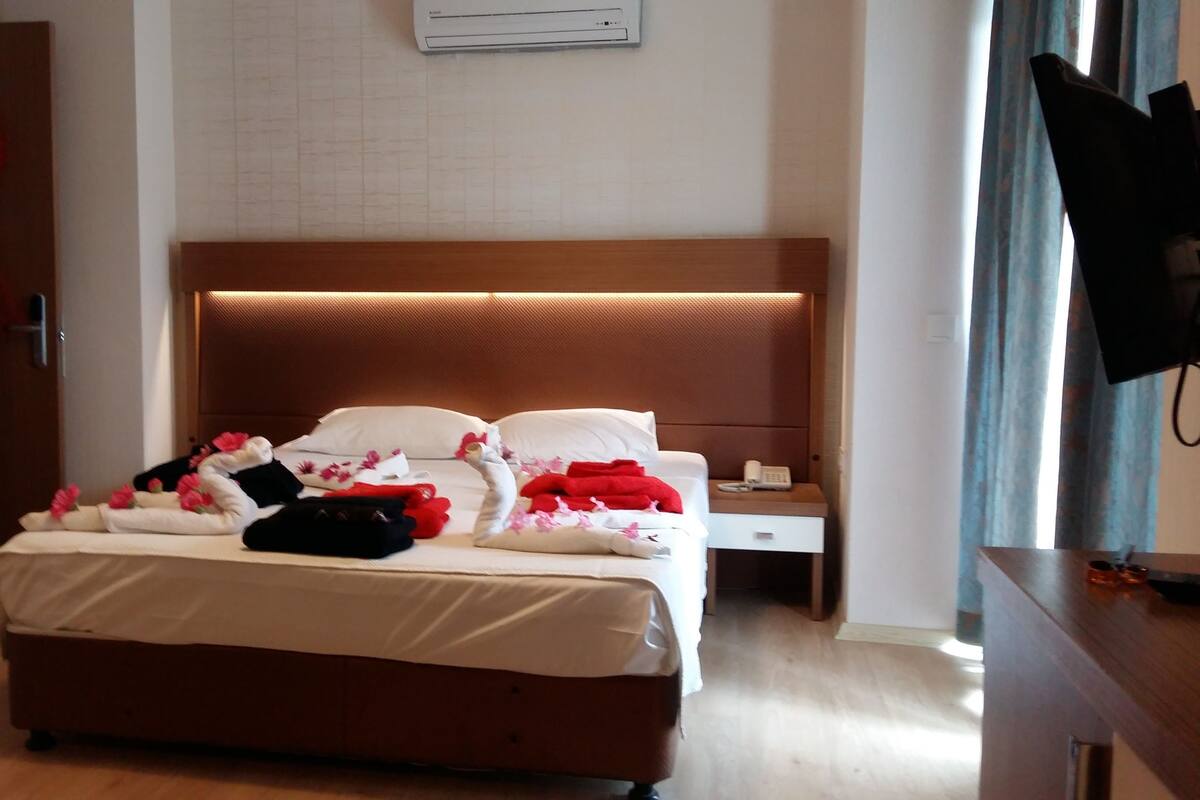 Une chambre d’hôtel avec un grand lit, une table de chevet avec un téléphone et un téléviseur posé sur un meuble.
