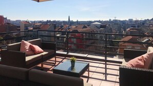 A balcony with a large umbrella, outdoor seating, and a view of a cityscape. - Porto Coliseum Hotel (Porto)