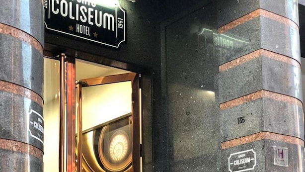 The entrance to the Coliseum Hotel with a grand revolving door, steps leading up to the entrance, and a sign above the door. - Porto Coliseum Hotel (Porto)