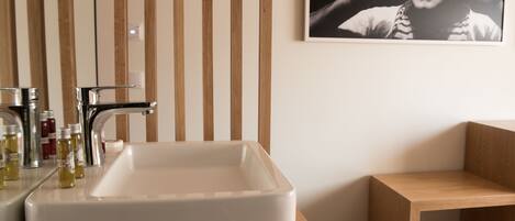 Une salle de bain avec un lavabo blanc, un robinet chromé et un lambris en bois sur le mur.