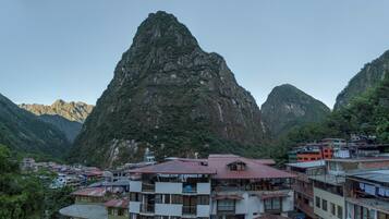 Un pueblo montañoso con edificios tradicionales y un pico prominente al fondo.