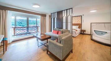 Habitación de hotel con balcón, cama, sofá, escritorio y bañera.