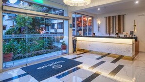 Ein Hotel-Empfangsbereich mit Marmor-Theke, einem Chandelier und Blick auf den Garten.
