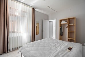 Un dormitorio moderno con una cama grande, un armario de madera y un espejo.