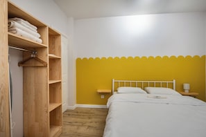 Ein Schlafzimmer mit einem Bett, einem Holzschrank, einem Nachttisch und einer Wand mit geschnitzter Verzierung.