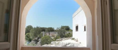 A balcony with a table and chairs, overlooking a rocky landscape and trees.