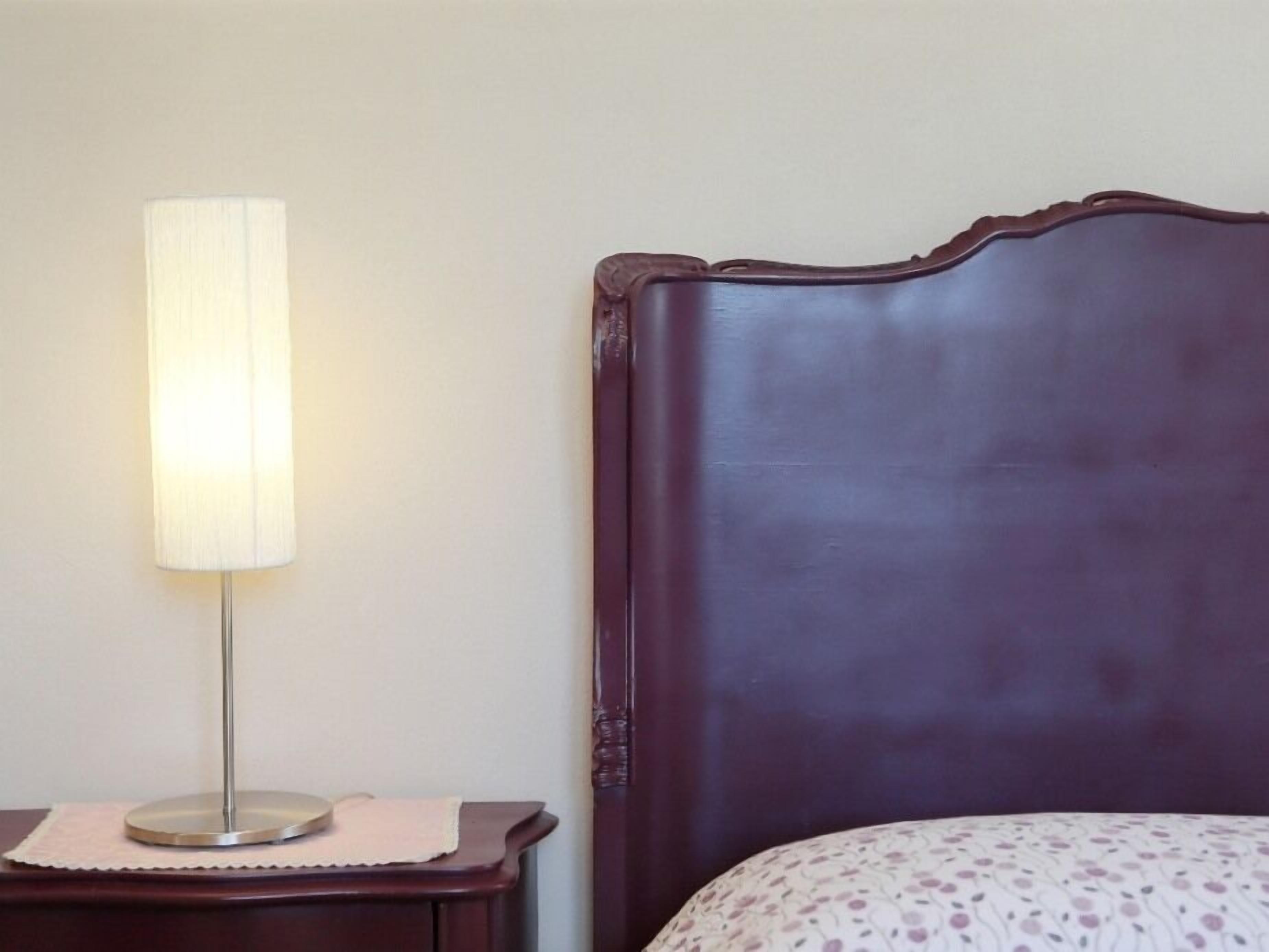 Un lit avec une tête de lit sombre et une table de chevet avec une lampe.
