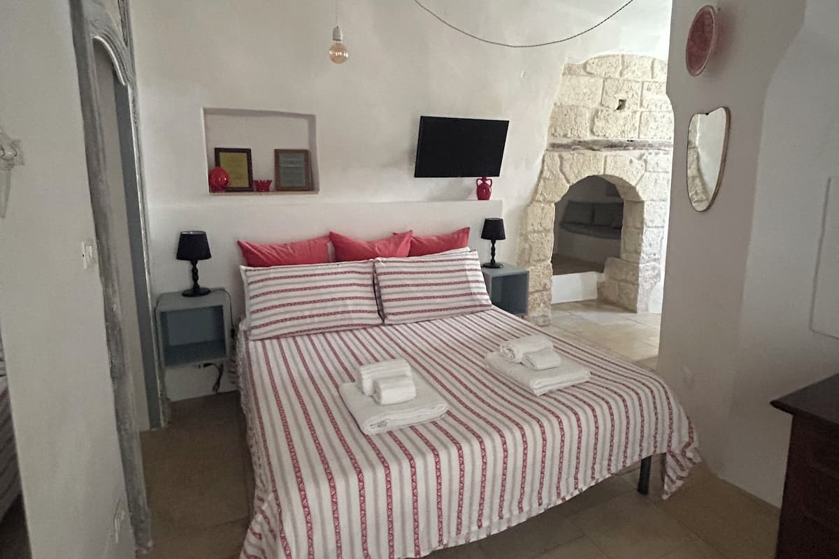 Een slaapkamer met een bed, een televisie, een stenen muur en een open haard.