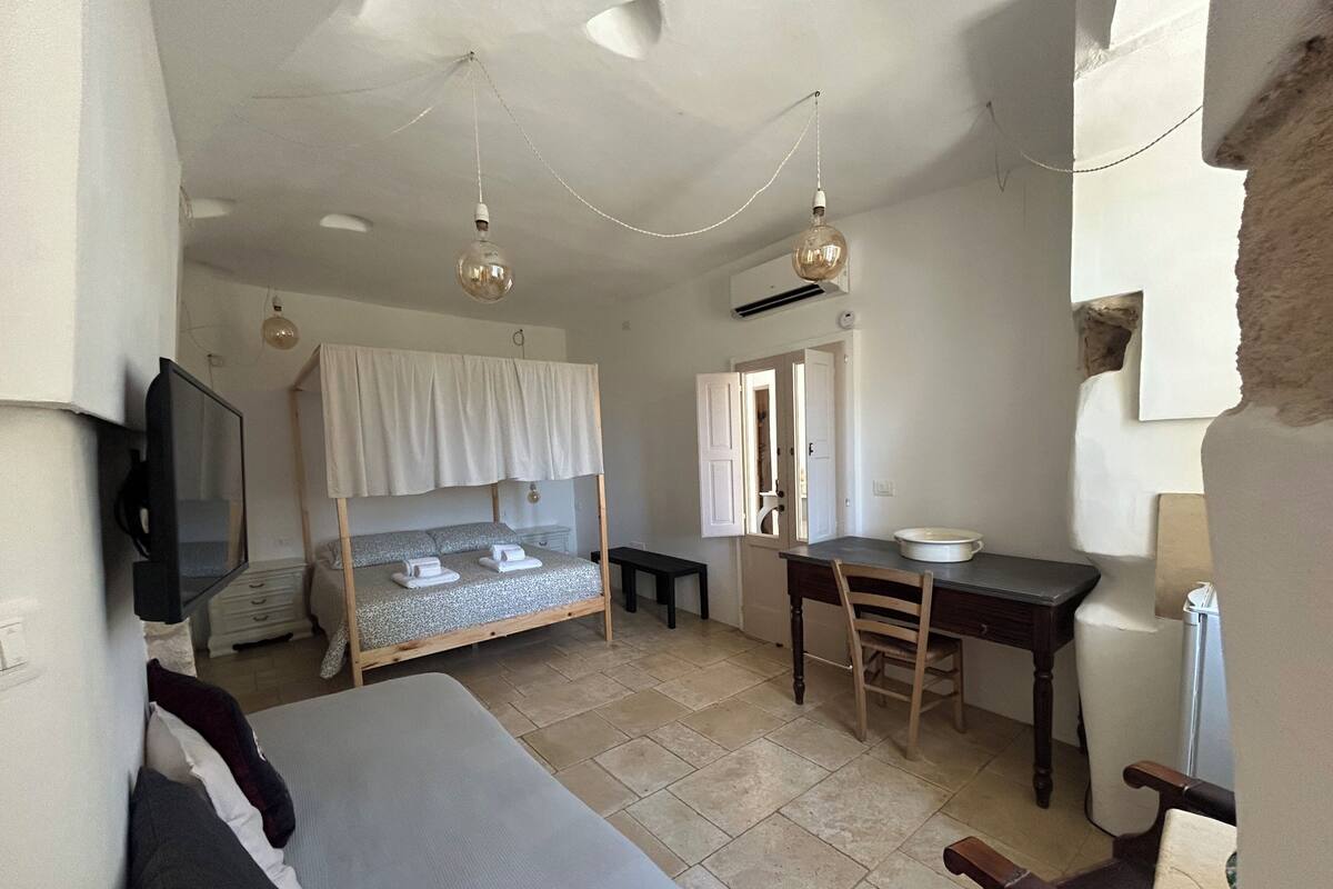 Een slaapkamer met een stapelbed, een bureau, een stoel, een televisie en een deur naar de badkamer.