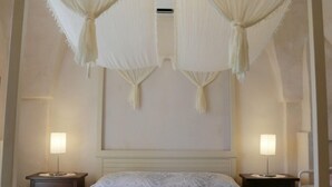Een slaapkamer met een bed, twee nachtkastjes en een wandairconditioner.