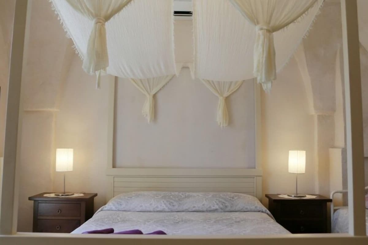Ein Schlafzimmer mit einem Bett, zwei Nachttischen und einer Wandklimaanlage.